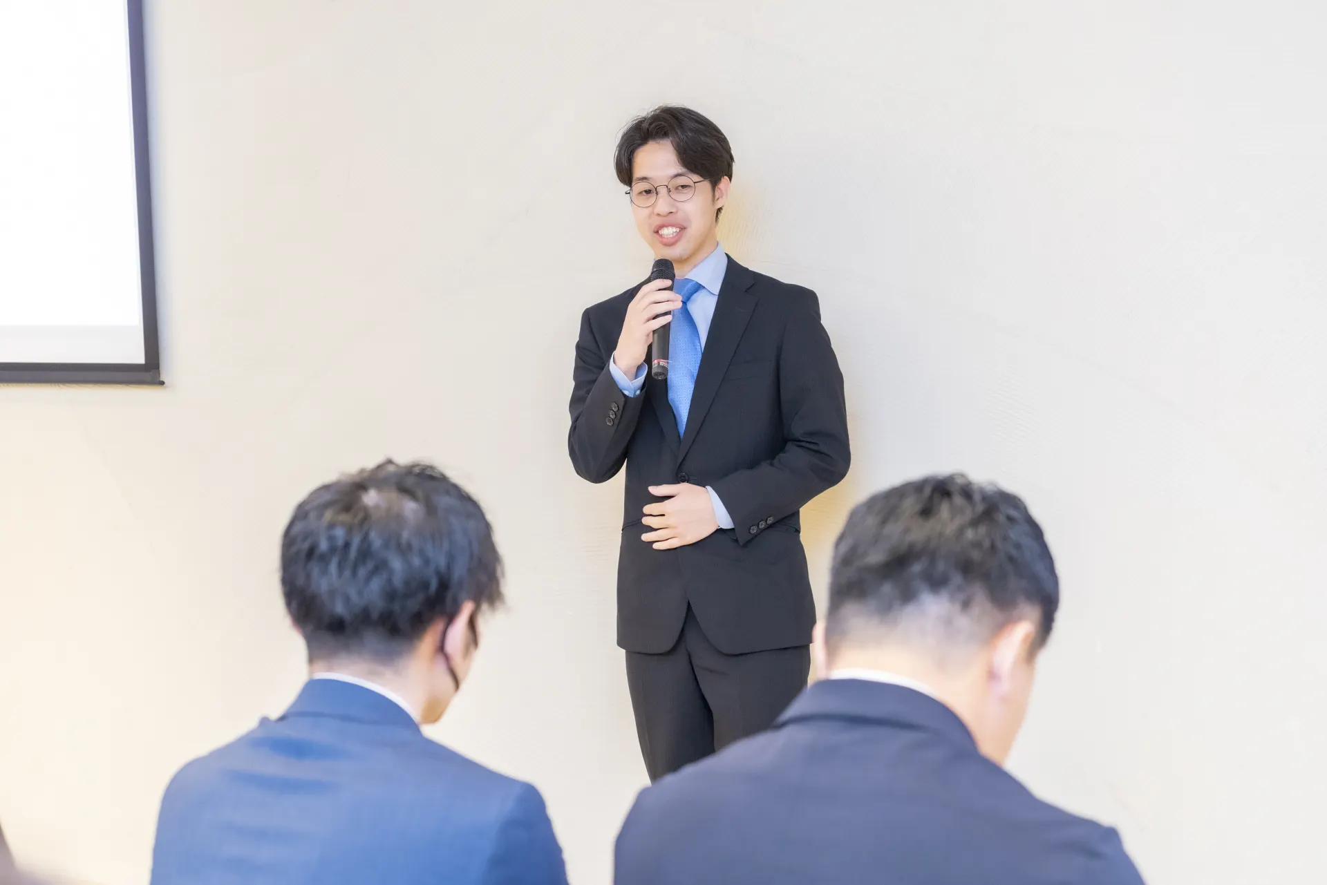 社内イベントでマイクを持って発表する社員