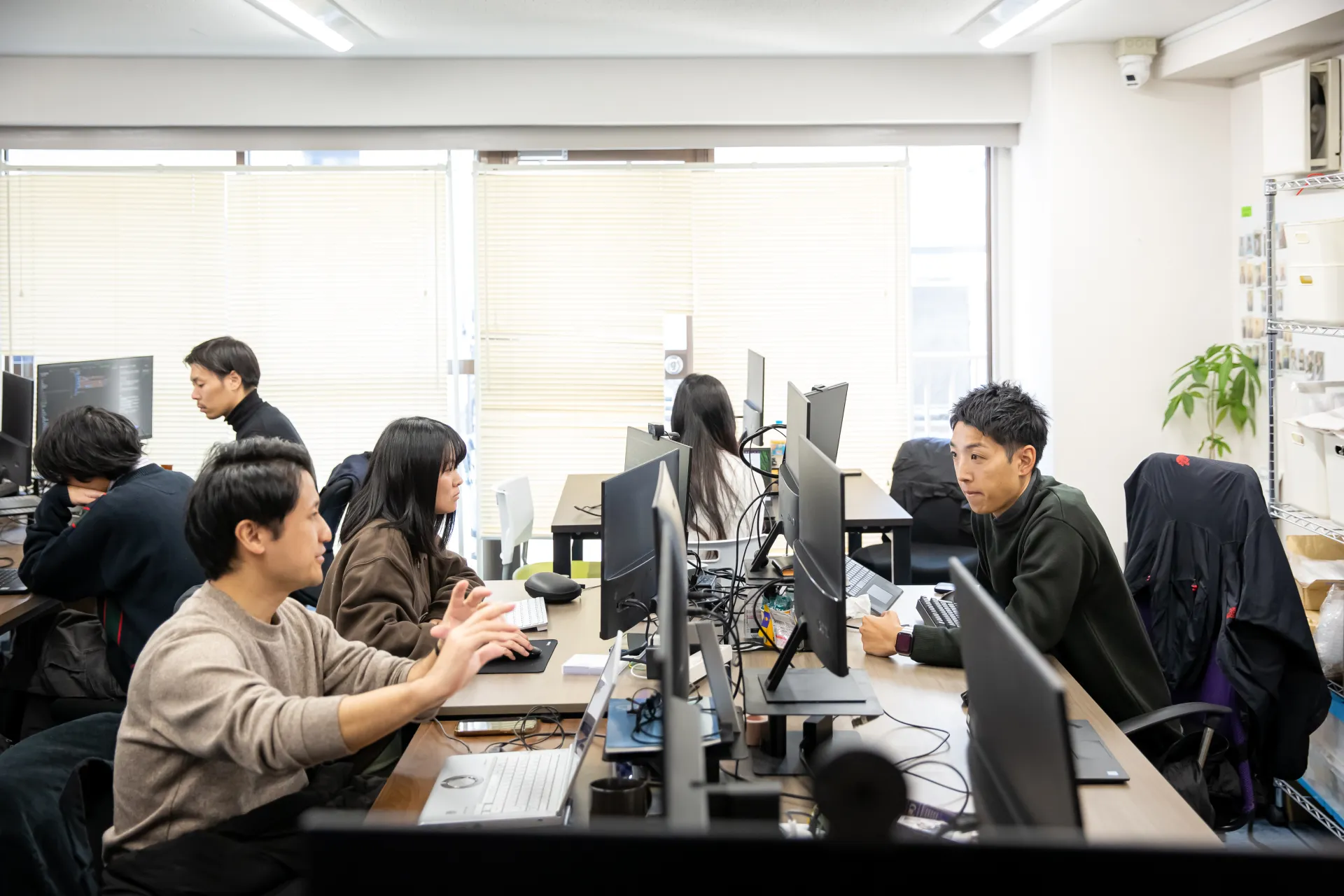 オフィスで業務や打ち合わせを行う社員たち